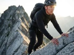 Articulated Knees Allow Full Range of Motion on Steps A professional climber executing a high-step mantle on a granite ridge, wearing Arc'teryx pants that demonstrate perfect articulated knee mobility.