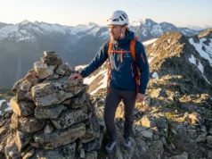 How to Read Class 3 Terrain Markers (And When to Ignore Them) Hiker in Petzl helmet reading rock cairn terrain markers on Class 3 alpine ridge at sunrise