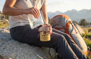 No Cook Backpacking Meals: What Works (And What Doesn’t) Hiker cold soaking no-cook backpacking meal in Talenti jar on alpine trail during golden hour