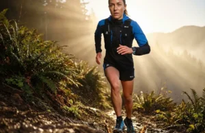 Deep Lugs Provide Traction on Muddy Slopes A low-angle, high-definition shot of a trail runner sprinting up a muddy slope, wearing Salomon gear, with sunlight backlighting flying mud particles while the runner remains pristine.