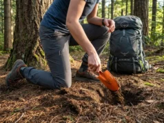 How to Dig a Proper Cathole for Human Waste Disposal Backpacker digging cathole with trowel in Pacific Northwest forest during morning light
