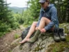 Double Sock System vs Single Layer: What 500 Miles Taught Me Hiker changing hiking socks on trail to prevent blisters during long-distance backpacking