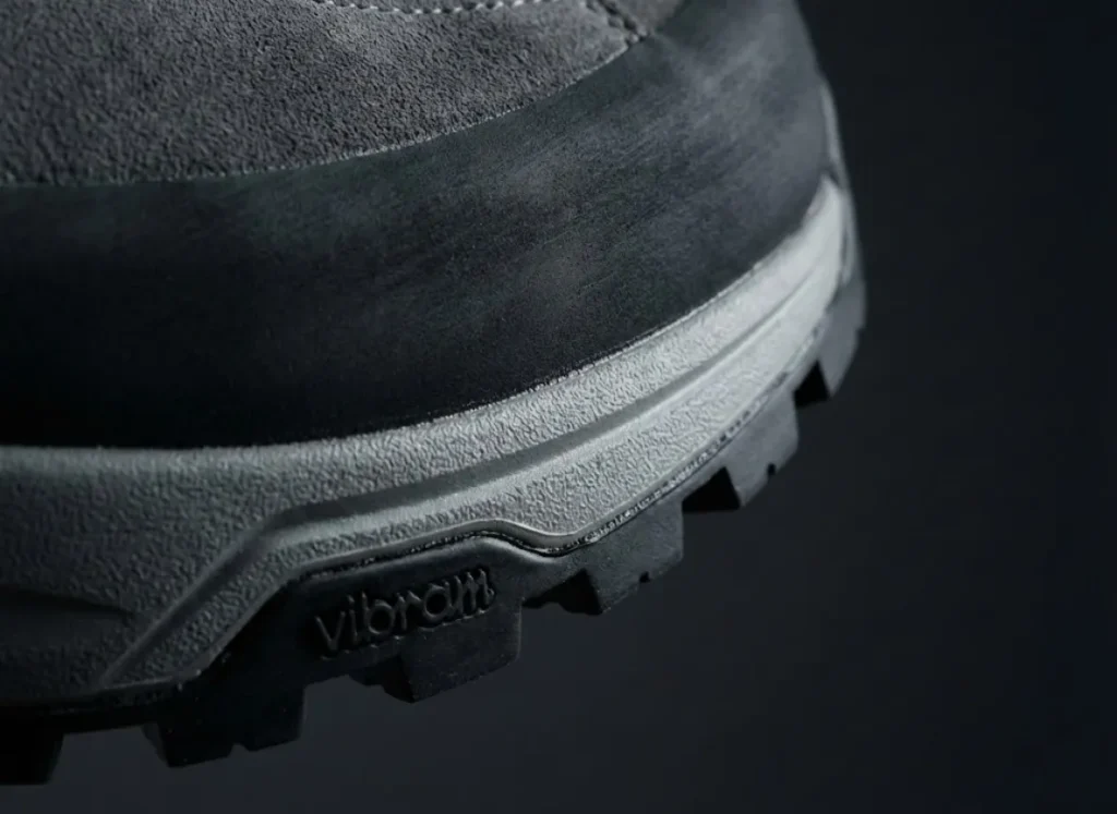 Macro photography close-up of the adhesive bond between the midsole and outsole of a Scarpa hiking boot, highlighting the polyurethane texture.