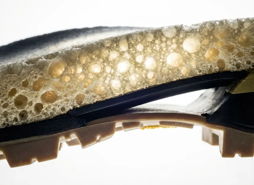 Macro profile shot of a hiking boot midsole showing the layers of Vibram rubber and porous Polyurethane foam to illustrate potential hydrolysis failure points.