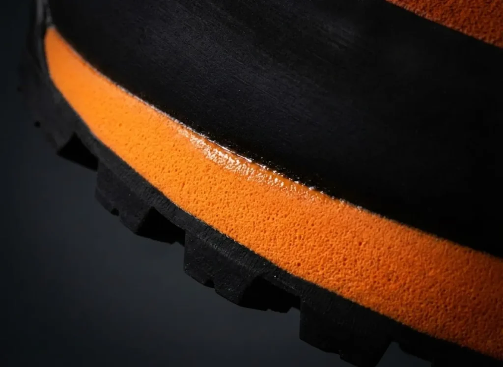 Extreme macro close-up of a Scarpa hiking boot midsole showing the texture of polyurethane foam and Vibram rubber, studio lighting.