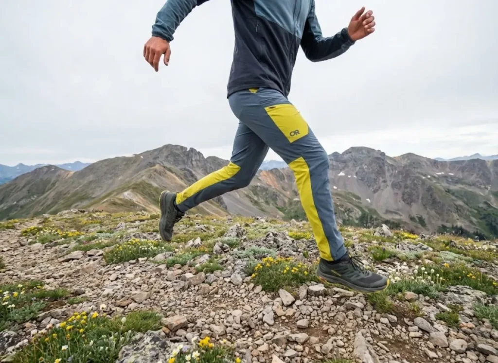 A fast-packing hiker leaping across rocks in stretch-woven pants, representing an agile mobility system.