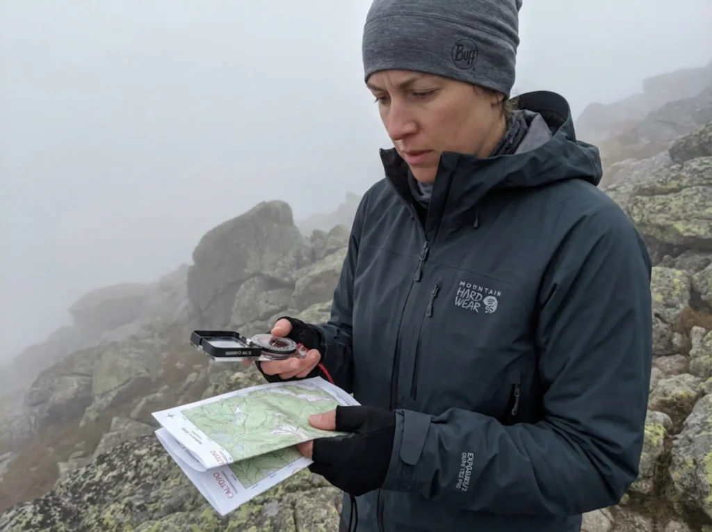Hiker navigating foggy Class 3 terrain with compass and topo map when markers are hidden