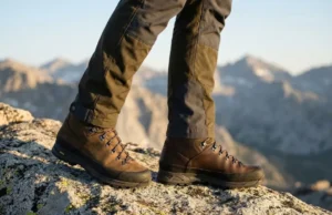 Nubuck Leather Breathability vs Full Grain Durability Close-up low angle shot of premium Lowa hiking boots on granite, contrasting the velvet texture of nubuck leather against the smooth finish of full-grain leather under golden alpine sunlight.