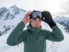 Stop Goggle Fogging on Winter Hikes: 7 Field-Tested Fixes Winter hiker examining fogged Smith goggles on snowy alpine ridge above treeline
