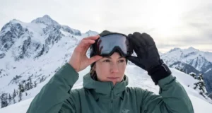Stop Goggle Fogging on Winter Hikes: 7 Field-Tested Fixes Winter hiker examining fogged Smith goggles on snowy alpine ridge above treeline