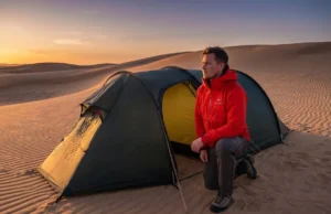 Stake Your Tent in Sandy Soil Using Deadman Anchors Professional hiker setting up a Hilleberg tent in vast sand dunes during golden hour, demonstrating pristine gear and technical focus.