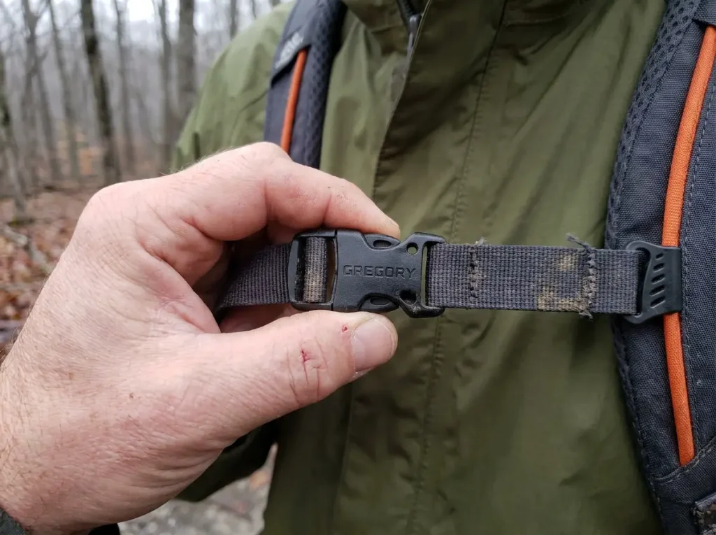 Close-up of a backpack sternum strap buckle showing the built-in emergency whistle port at chest level