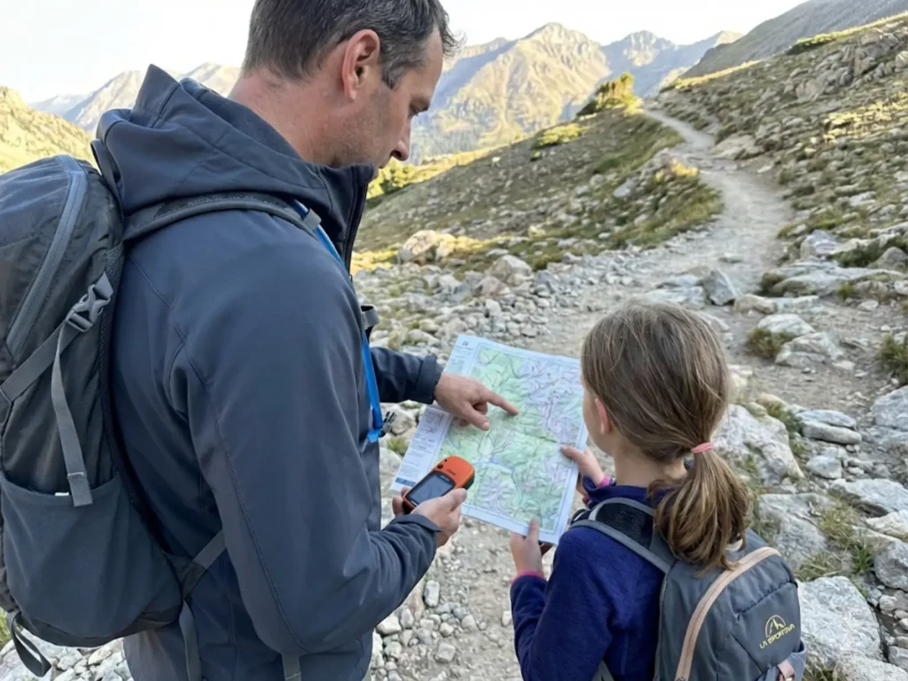 Father and daughter studying trail map and elevation at mountain junction