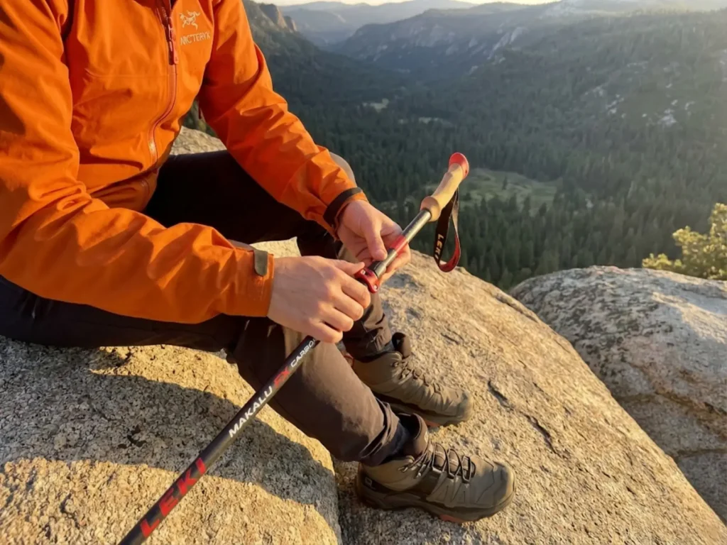 Hiker adjusting lever lock on aluminum trekking pole during trail break