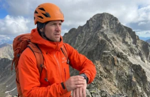 Calculating Turnaround Time: The Math That Saves Lives Mountaineer checking GPS watch on alpine ridge deciding turnaround time for summit attempt