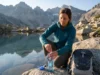 UV Water Purifiers for Hiking and the Battery Problem Hiker using SteriPEN UV water purifier to treat water from alpine lake at sunrise