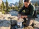 The Right Way to Wash Your Hiking Socks on Trail Hiker washing Merino wool socks using Leave No Trace oven bag method 200 feet from alpine stream