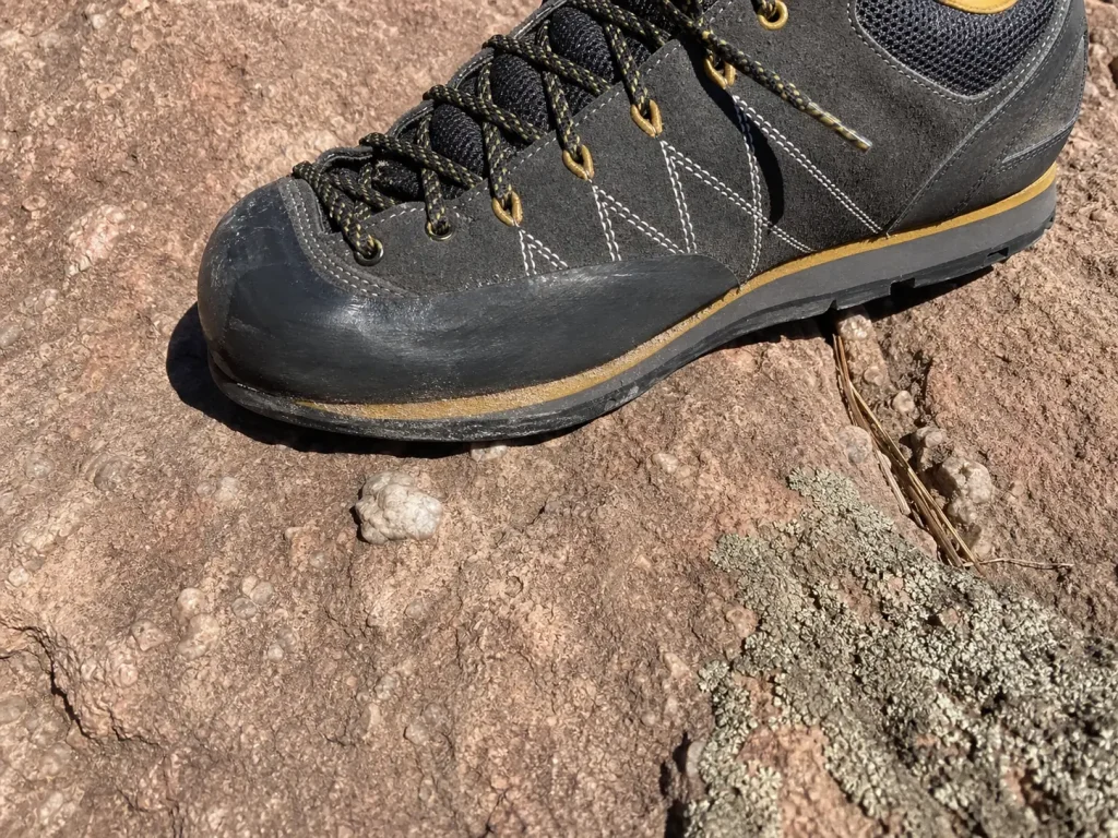 Close-up of an approach shoe smearing flat on Flatirons sandstone, showing the sticky toe rubber