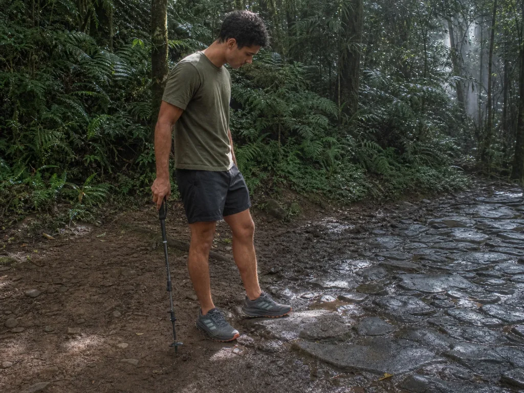 Hiker choosing a line across mixed wet rock and mud terrain in trail shoes with Continental rubber