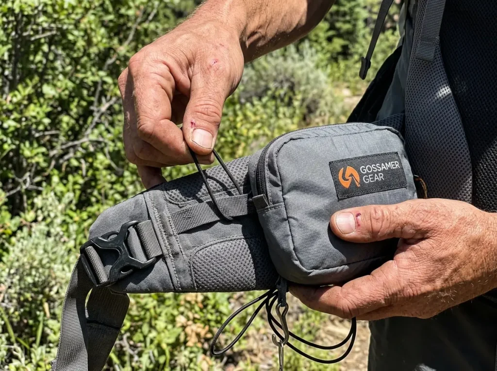 Hands cinching a Gossamer Gear add-on hip belt pocket onto a backpack belt with cord loops
