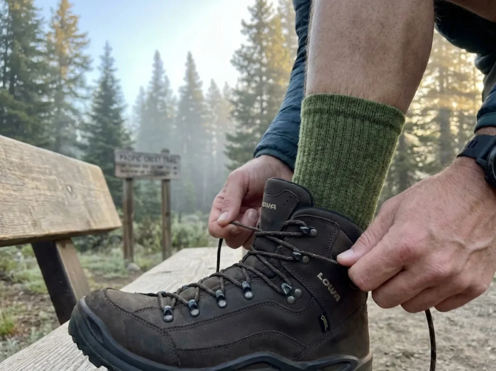 Crew sock cuff extending above hiking boot collar creating proper abrasion buffer zone