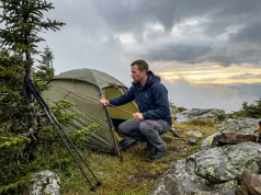Wind and Rain Wrecked My Camp. Here’s What I Changed Hiker assessing wind-damaged tent on mountain campsite after rain storm