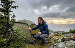 Wind and Rain Wrecked My Camp. Here’s What I Changed Hiker assessing wind-damaged tent on mountain campsite after rain storm