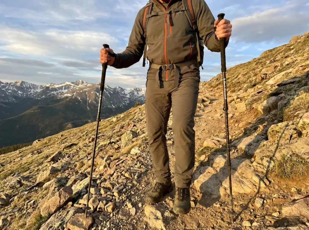 Hiker using EVA foam grip trekking poles for shock absorption on a rocky alpine descent