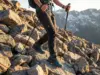 Matching Hiking Pant Length to Terrain Types Hiker descending rocky terrain with hiking pants fitted above boot cuff for foot visibility