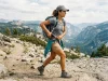Best Hip Belt Pockets That Won’t Bounce 2026 Hiker pulling a phone from a hip belt pocket on an Osprey pack mid-stride on a ridge trail