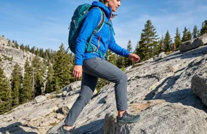Stop Rolling Your Hems. These Petite Pants Work. Petite woman hiker in Outdoor Research Ferrosi pants stepping over granite boulder on alpine trail