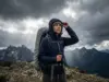 Which Rain Jacket Fails First on the Trail Hiker adjusting Patagonia rain jacket hood as storm approaches alpine ridge