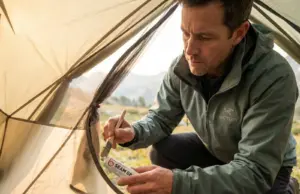 After 50+ Tents Sealed, This Is What Actually Works Hiker applying seam sealer to tent interior seams with brush during backcountry maintenance