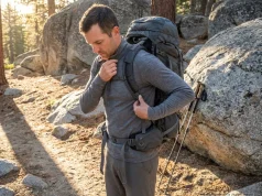 I Hiked 200 Miles Testing Snug vs Loose Base Layers Hiker adjusting Smartwool base layer fit under loaded pack on Sierra trailhead at golden hour