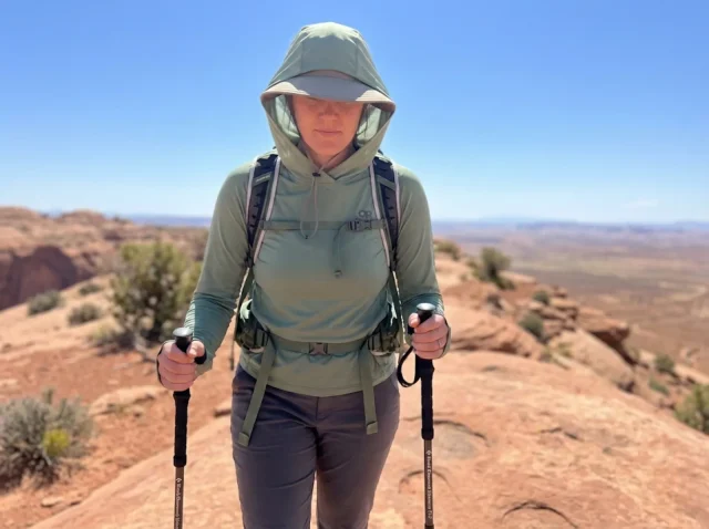 sun-hoodie-upf-hiking-hot-weather-hero Hiker wearing a sun hoodie with hood up crosses an exposed desert ridge in brutal heat