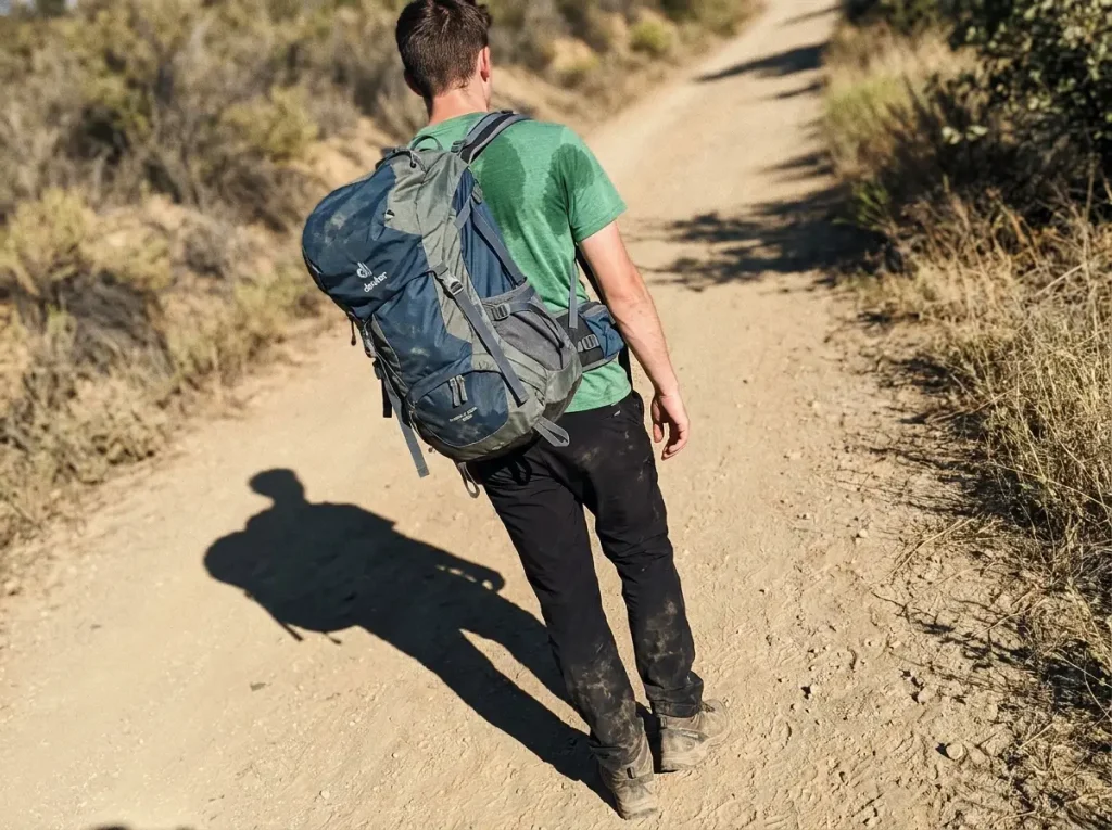 Hiker with an oversized half-empty pack sagging and swaying to one side on the trail