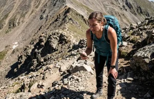 Why That “Moderate” Trail Wrecked You Last Weekend Hiker stopping on steep rocky trail checking trail difficulty rating on phone — trail difficulty rating systems