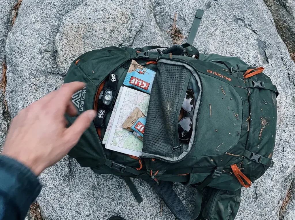 Top-down view of a Gregory Baltoro brain lid unzipped showing headlamp, map and snacks