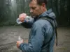3 Rain Jacket Care Windows That Matter Most Hiker checking the shoulder of a rain jacket for water beading after a wet morning on the trail