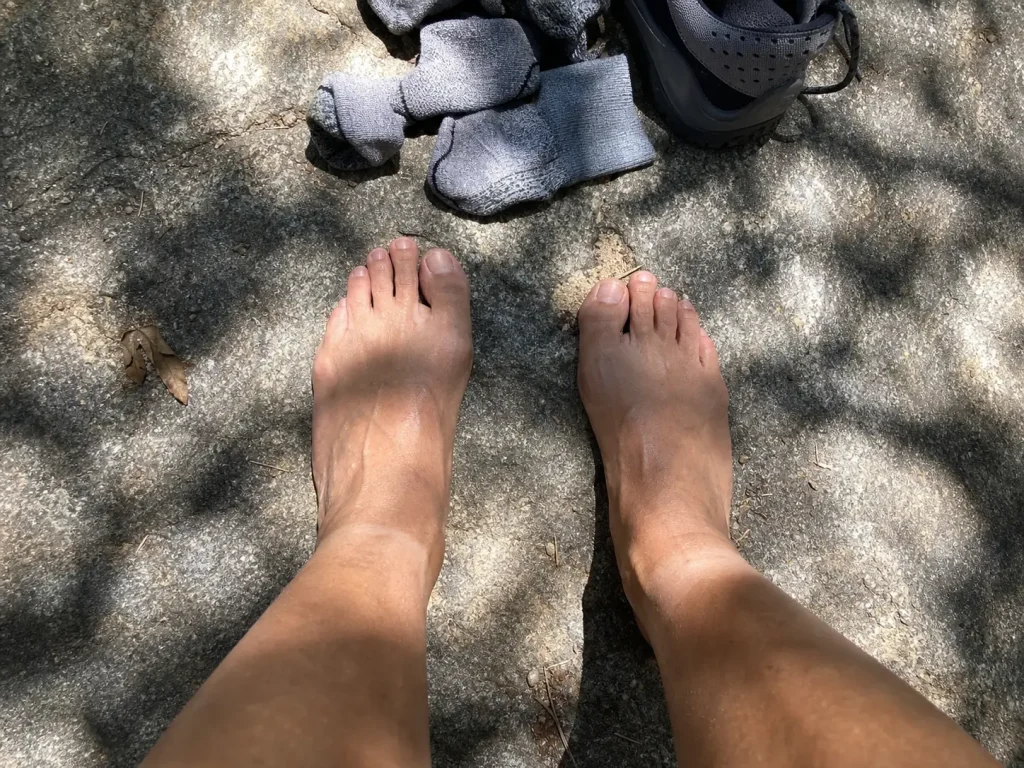 Bare feet on a warm rock showing a low arch, the flat foot shape behind hiking shoe choice