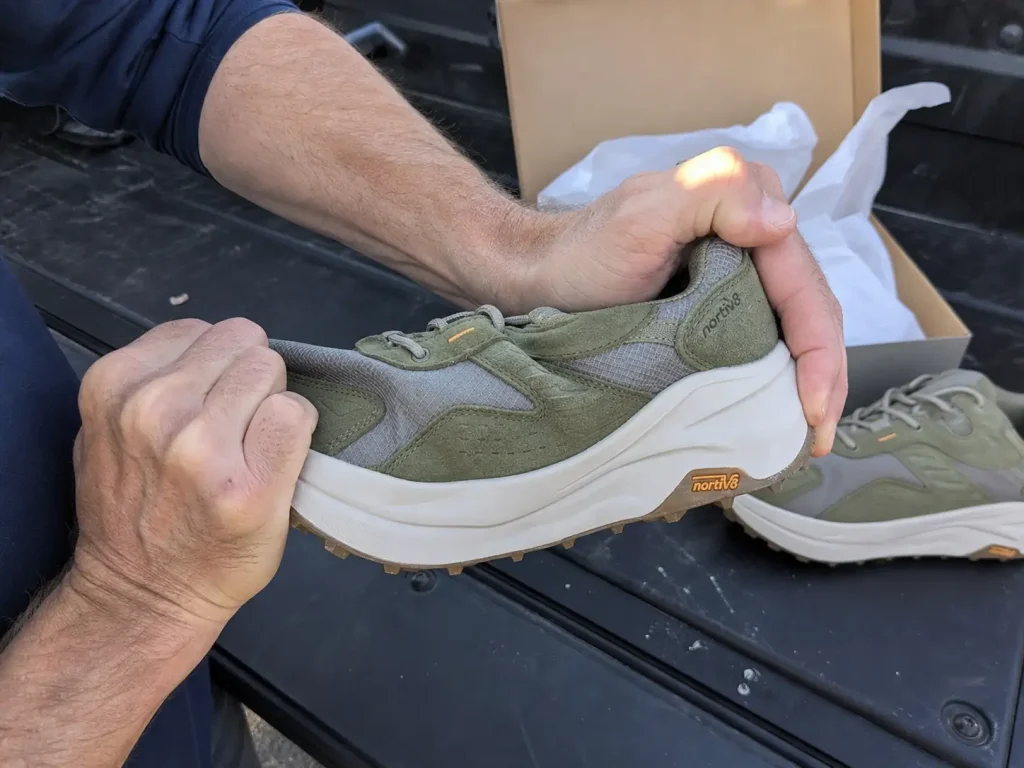 Hands twisting a hiking shoe to test torsional rigidity, the shelf test for flat feet support