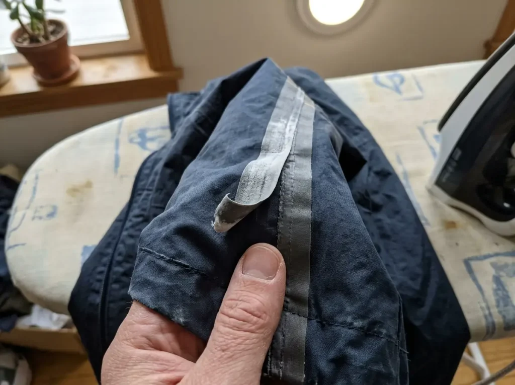 Close-up of taped seams inside a rain jacket showing where repeated washing eventually wears