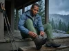 Dry Hiking Boots Overnight the Field-Tested Way Hiker removing lace from soaked Lowa hiking boot on mountain hut porch after a wet trail day
