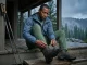 Dry Hiking Boots Overnight the Field-Tested Way Hiker removing lace from soaked Lowa hiking boot on mountain hut porch after a wet trail day