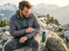 How to Patch a Down Jacket on Trail (The 5-Minute Fix) A hiker repairing a torn grey Patagonia down jacket sleeve with Tenacious Tape on an alpine ridge.