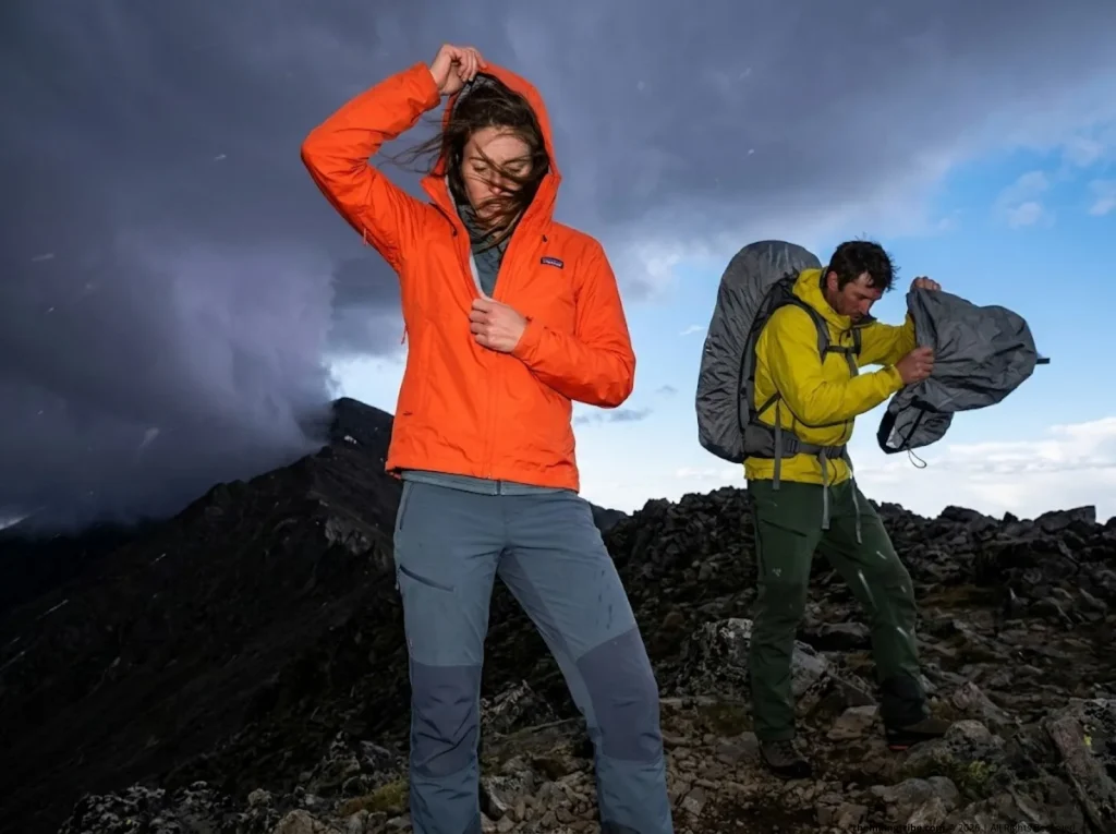 Hikers putting on waterproof gear during sudden mountain thunderstorm