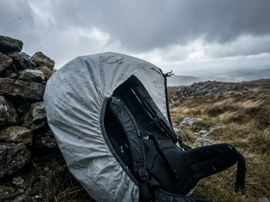 Wind lifting a rain cover off a backpack's back panel, showing why a cover alone won't waterproof a backpack