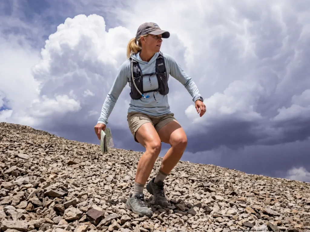 Trail runner rapidly descending scree slope to evade summer convective thunderstorm