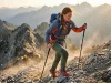 What Is Fastpacking? Gear & Pace Guide For Big Miles Female fastpacker power-hiking a steep rocky ridge wearing a lightweight vest pack and windbreaker at sunrise.
