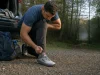 Best Hiking Shoes for Wide Feet When Roomy Isn’t Enough Hiker relacing an Altra Lone Peak 9 at a trailhead, the wide toe box visible on the shoe